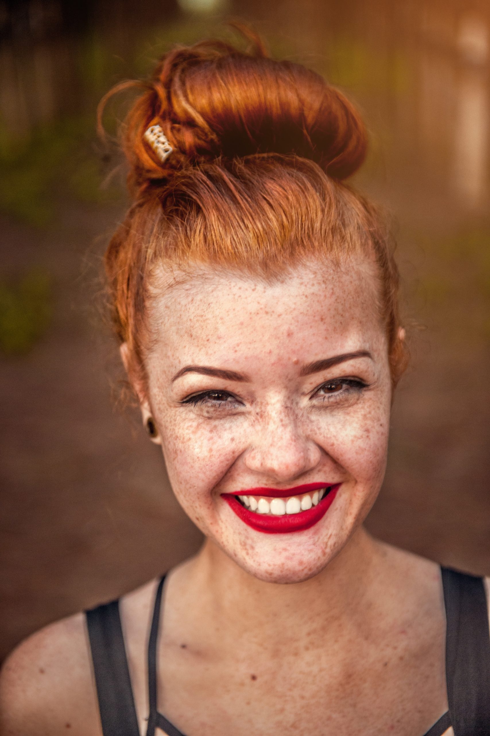 Junge Frau mit roten Haaren lächelt.